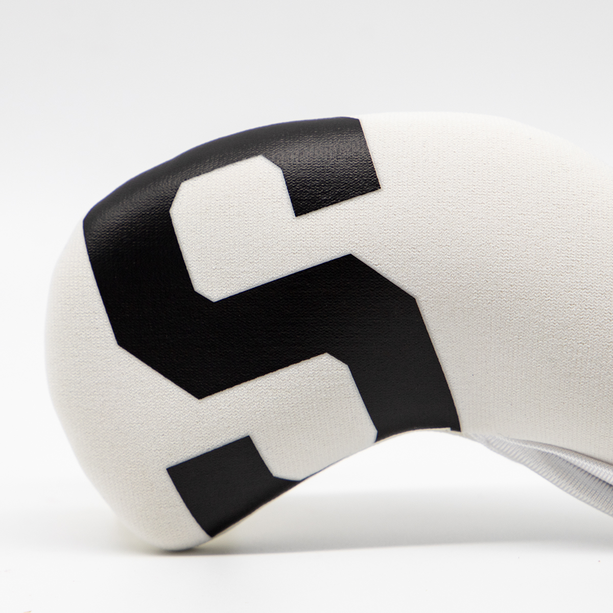 A close-up of a white cover shows a large black “5” marking.