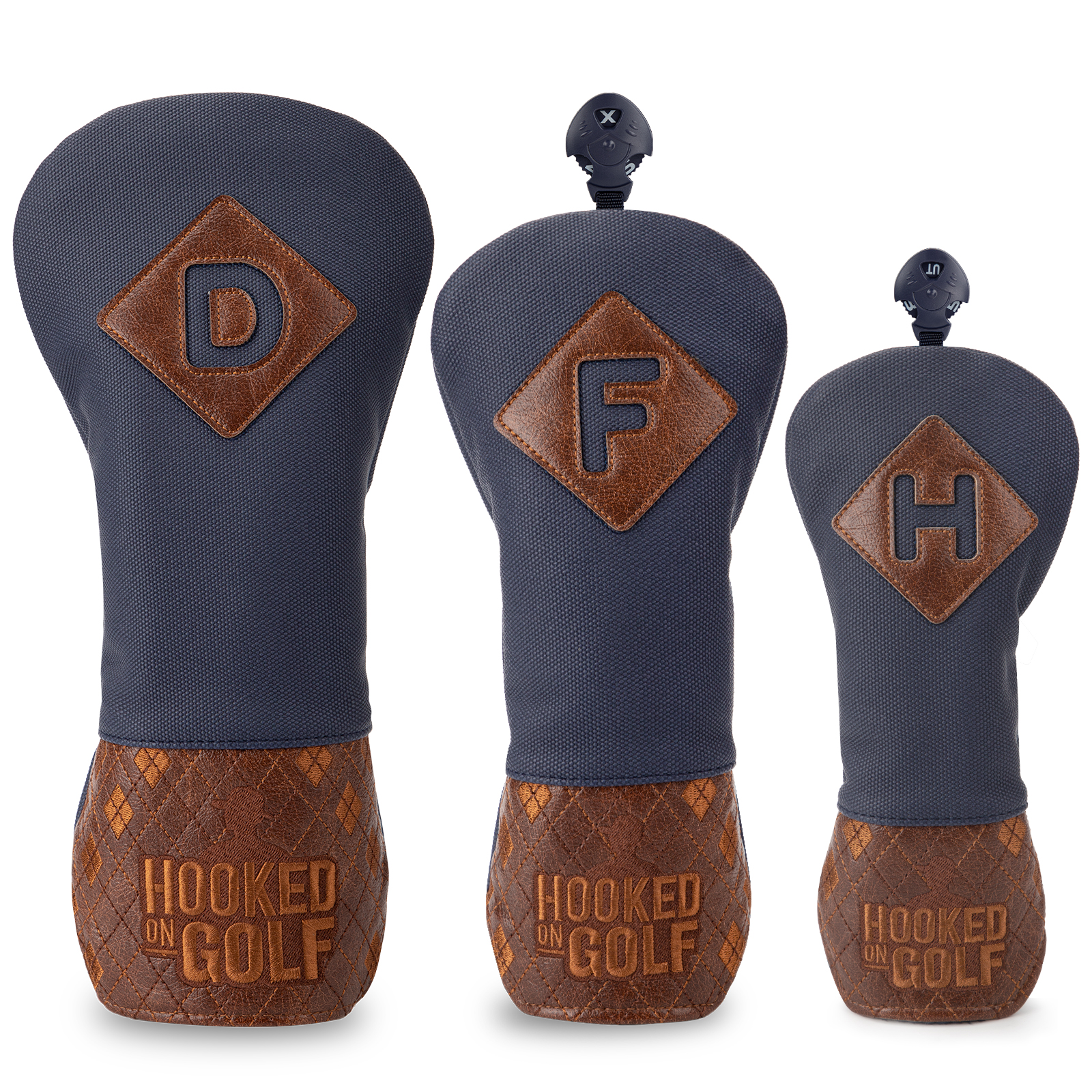 Three navy covers with brown diamond-shaped letter patches and patterned brown lower sections, shown upright.