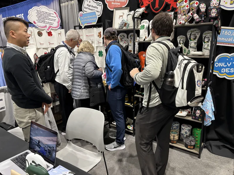 People standing beside an indoor golf-merchandise display