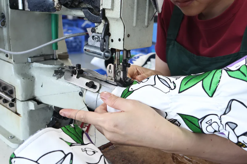 Hands guiding patterned fabric under a sewing-machine needle