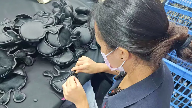 Hands finishing shaped fabric pieces at a worktable