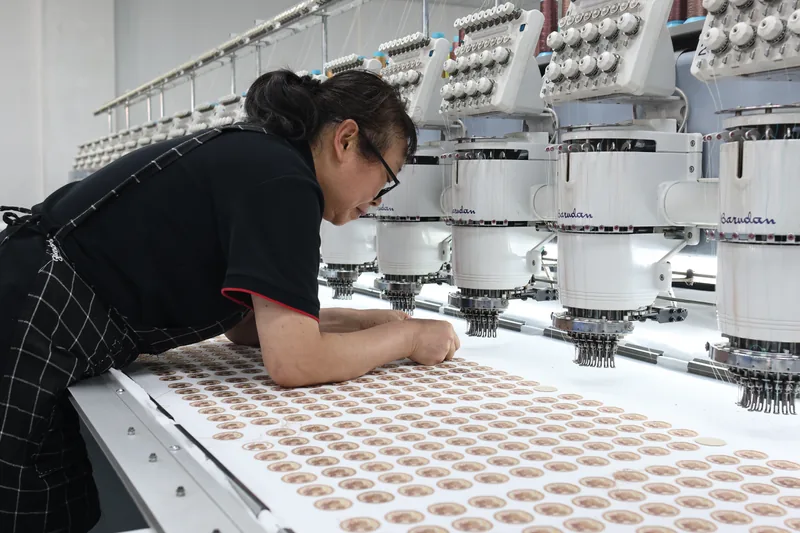 Person working beside a multi-head embroidery machine